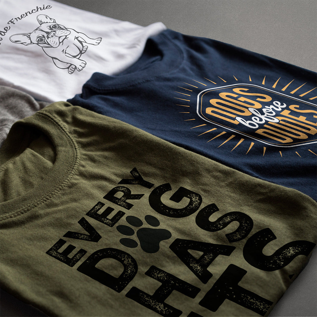 Flat lay of three Hero & Starr graphic tees—‘Tour de Frenchie,’ ‘DOGS before DUDES,’ and ‘EVERY DOG HAS ITS DAY—highlighting dog lover apparel styles.